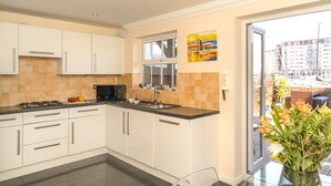 Une cuisine moderne avec des meubles blancs, un micro-ondes noir et une fenêtre donnant sur un paysage urbain.