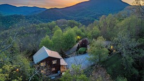 Une cabane dotée d’un toit en pente, entourée d’une forêt dense et de montagnes.