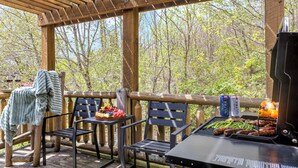 Un espace extérieur abrité comprenant un barbecue, des sièges et une table avec de la nourriture et des boissons.