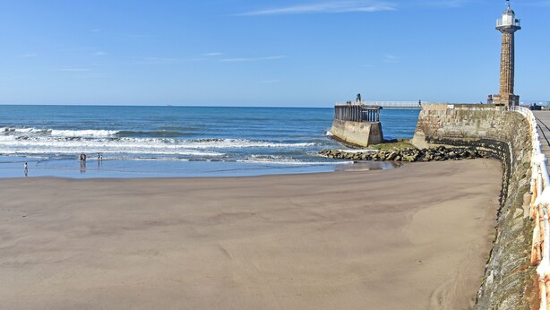 A coastal scene with a lighthouse, a pier, and a sandy beach. - 2 bedroom accommodation in Whitby (Whitby)