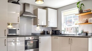 A modern kitchen with white cabinets, stainless steel appliances, a built-in oven, and a window with a view of the outside. - 2 bedroom accommodation in Whitby (Whitby)