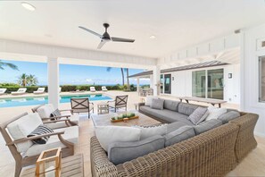 Ein moderner Außenbereich mit Pool, Sitzgelegenheiten und Deckenventilator.