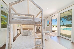 Ein Schlafzimmer mit Etagenbetten und Blick auf Pool und Palmen.