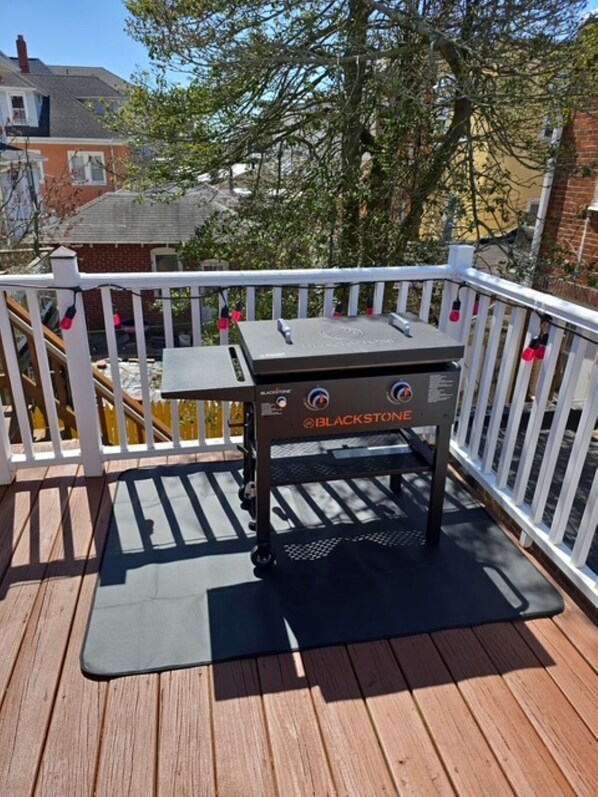 Ein Blackstone-Grill auf einer Holzterrasse mit weißer Geländer.