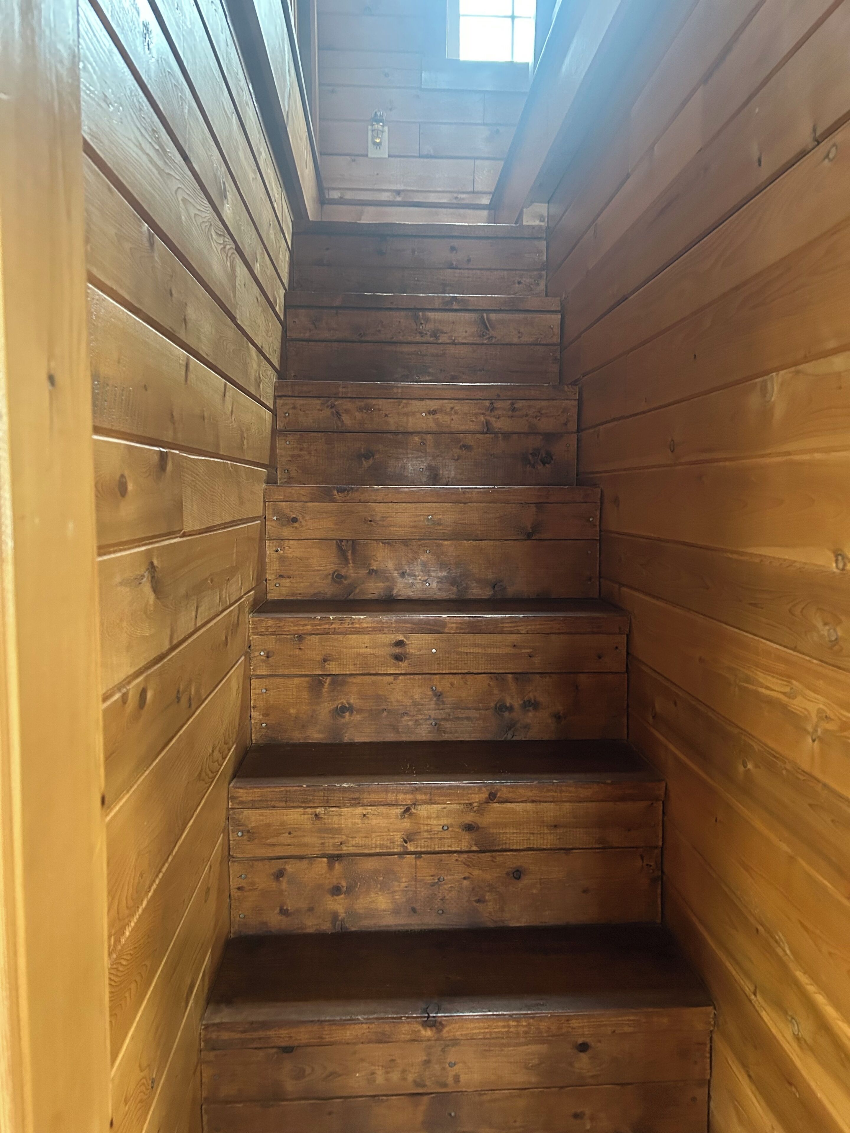 A wooden staircase with a skylight at the top.