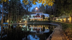 Un hôtel situé au bord d’un lac, dont l’image se reflète dans l’eau, avec un quai et un sentier longeant la rive.