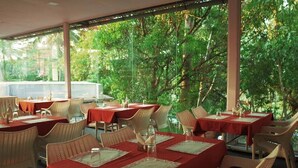 Un restaurant en plein air, avec des tables disposées pour accueillir les clients, entouré d’arbres.