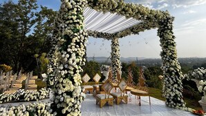 Une cérémonie de mariage en plein air, avec une arche décorée de fleurs et un espace réservé aux invités.
