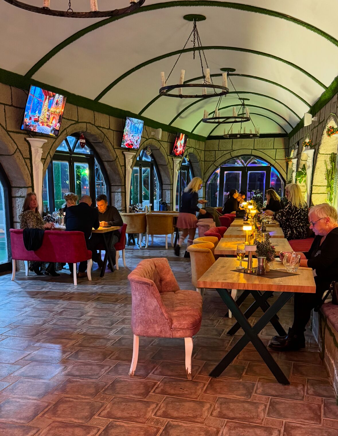 Un restaurant doté d’arches en pierre, de tables en bois et de sièges confortables.