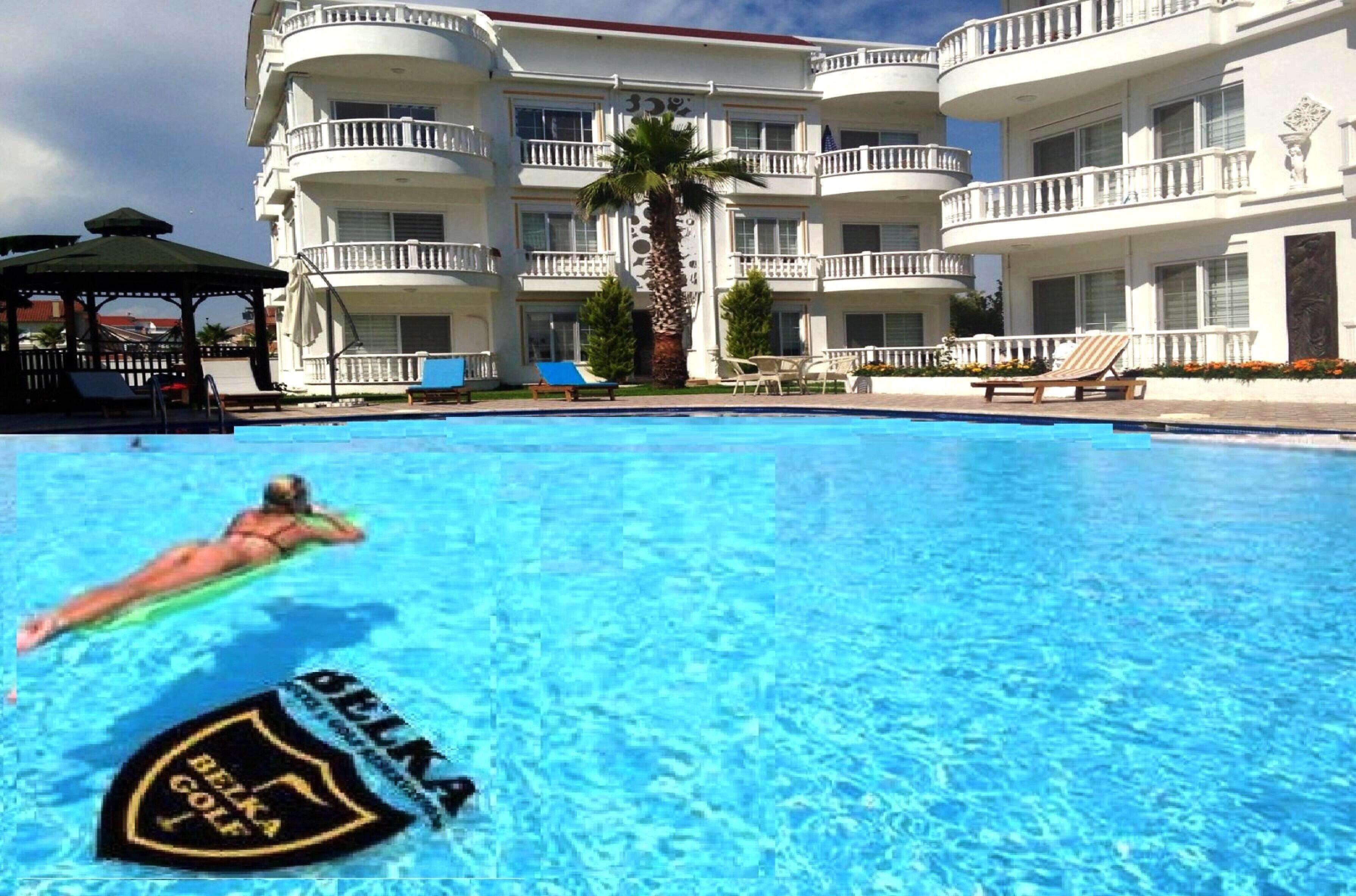Un hôtel doté d’une piscine, de plusieurs balcons et d’un palmier.