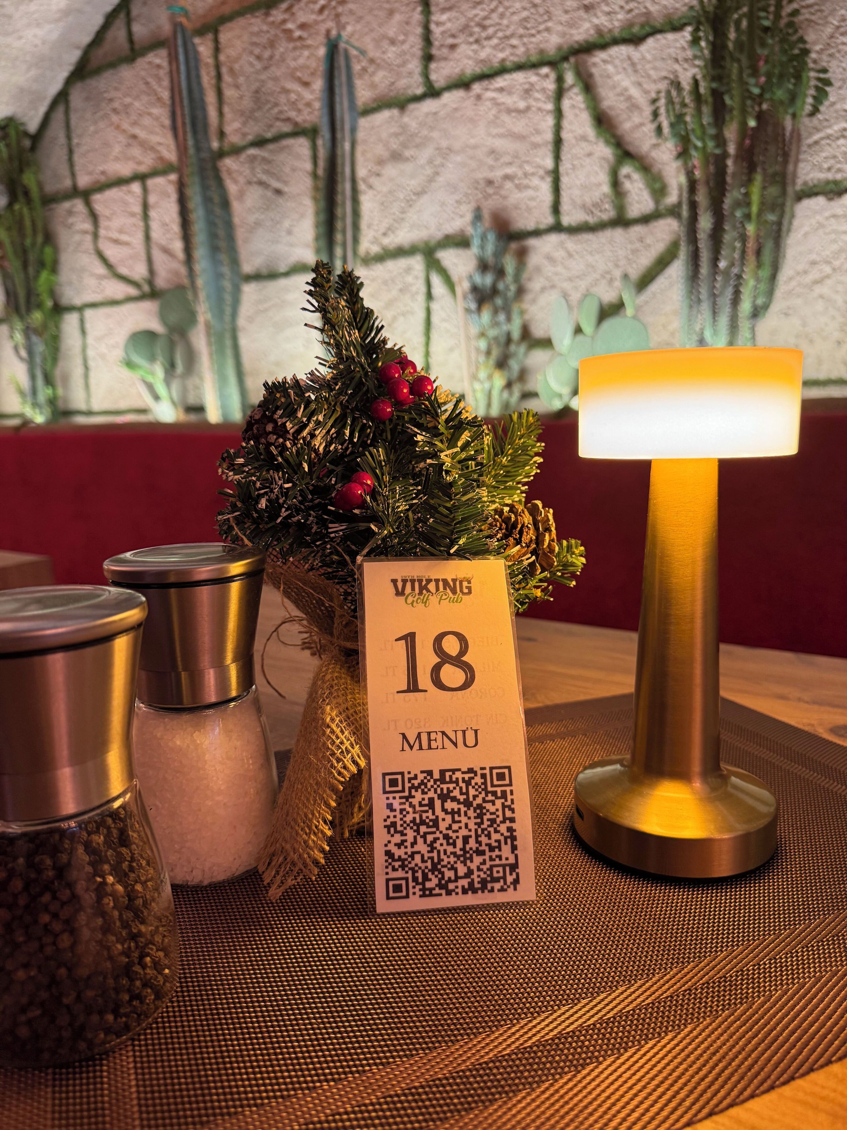 A table with a menu sign, a decorative plant, and a table lamp.