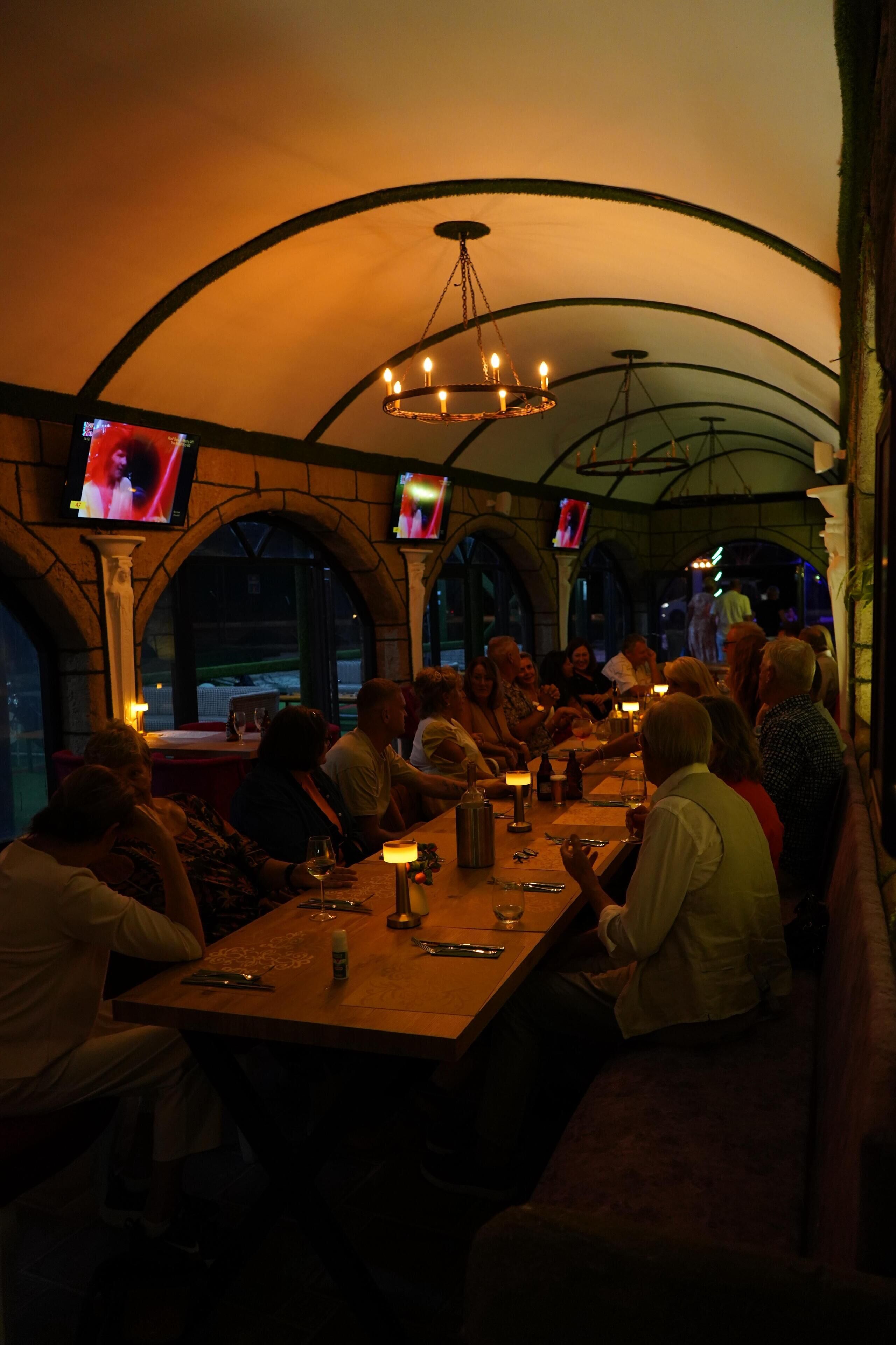 Un restaurante con techo abovedado y varias pantallas de televisión mostrando contenido.