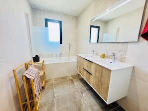 Een moderne badkamer met een houten wastafel, een bad en een grote spiegel.