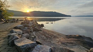 Une vue sur le lac, avec une terrasse en bois, des chaises et un mur en pierre.