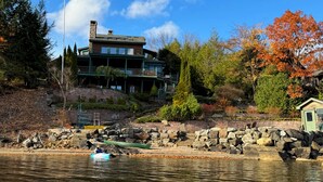 Une propriété au bord du lac, comprenant une grande maison, un quai et un petit bateau.