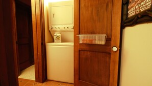 A laundry room with a washing machine, a dryer, and a small storage bin on the wall.
