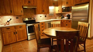 A kitchen with wooden cabinets, a stainless steel refrigerator, a microwave, and a stove.