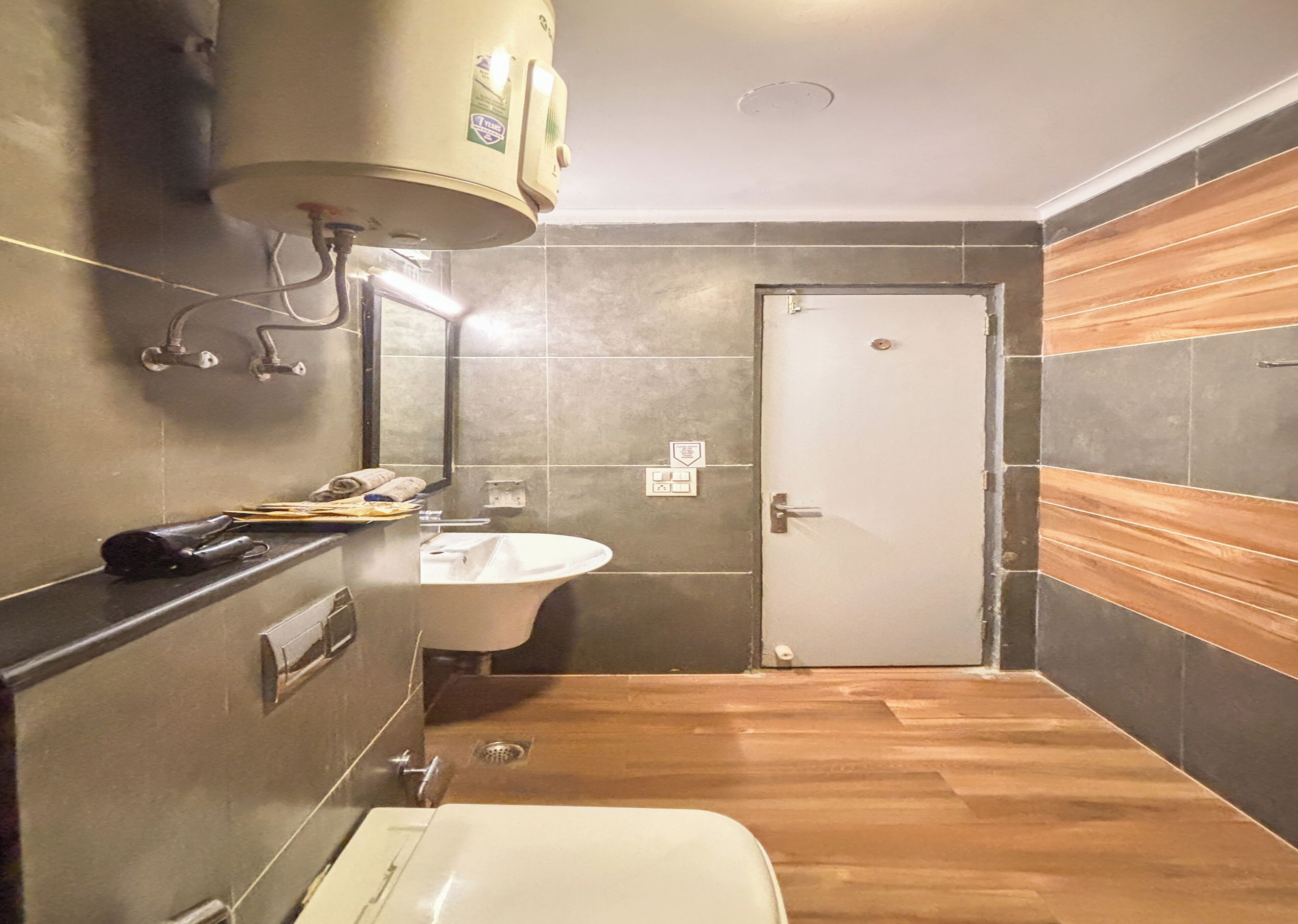 A compact bathroom with a white sink, a bathtub, and a toilet. There is a towel rack and a heater mounted on the wall.