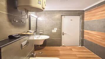A compact bathroom with a white sink, a bathtub, and a toilet. There is a towel rack and a heater mounted on the wall.