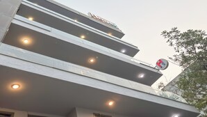 Een modern gebouw met meerdere balkons en een bord waarop een hotel wordt aangegeven.