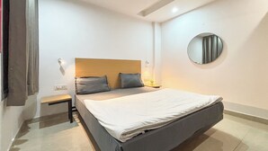 Een moderne slaapkamer met een groot bed, een nachtkastje, een ronde spiegel en een plafondventilator.