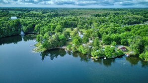 Ein Luftbild eines Sees mit mehreren Ferienhäusern und einem großen Haus, umgeben von dichtem Wald und einem ruhigen See.