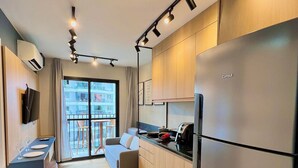 Une cuisine moderne dotée d’un grand réfrigérateur, d’un coin repas avec une table et des chaises, et offrant une vue sur la ville grâce à de grandes fenêtres.
