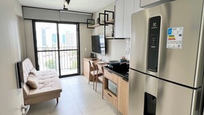 Une cuisine moderne équipée d’appareils électroménagers en acier inoxydable, un canapé et un coin repas avec des chaises.