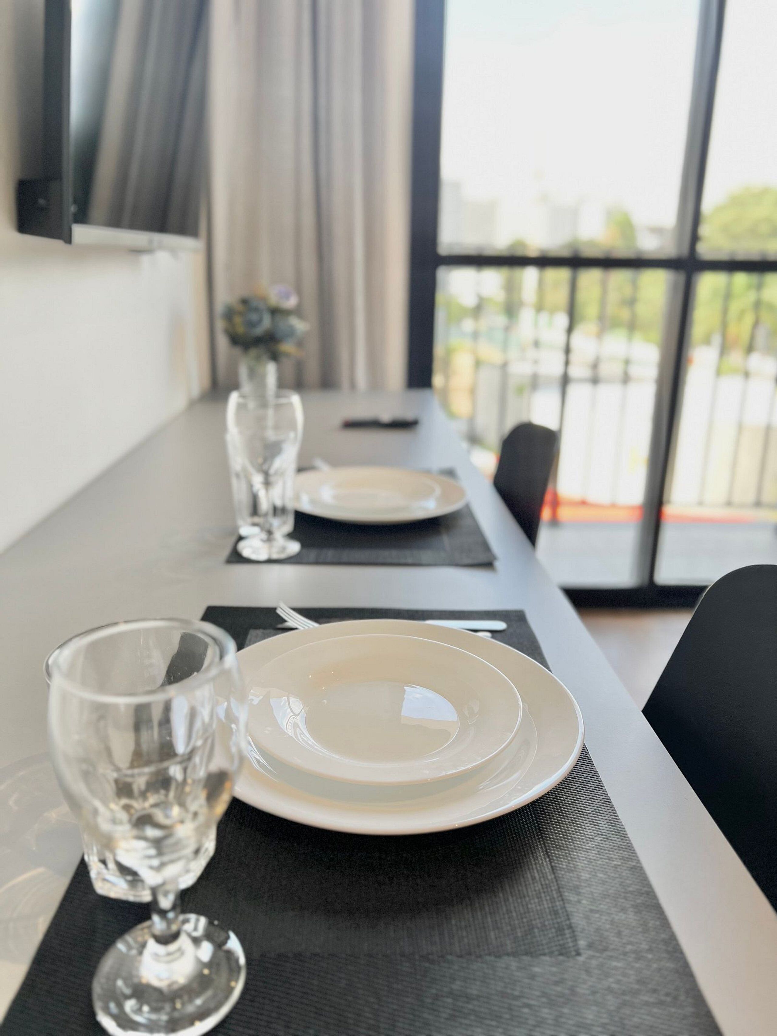 Une table à manger dressée avec des assiettes, des verres et un vase rempli de fleurs.