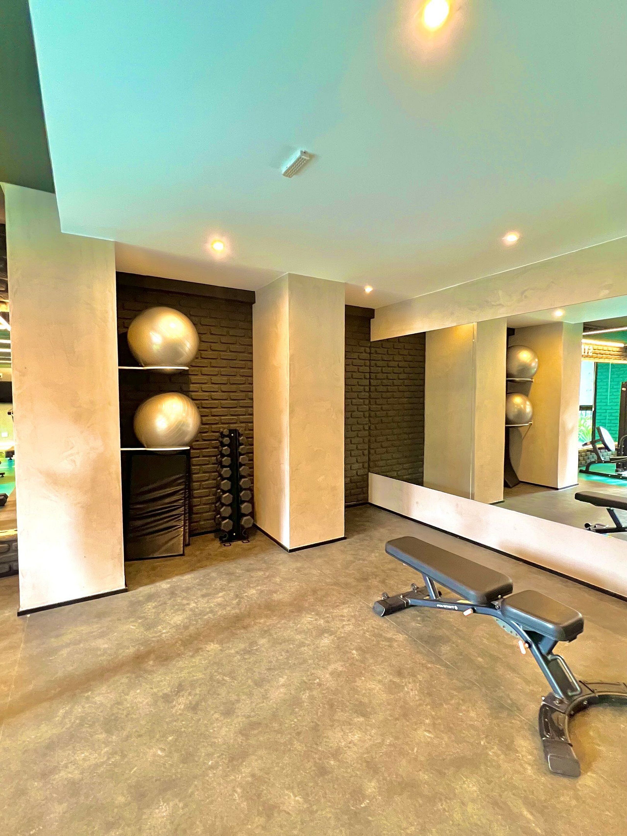 A modern gym with a bench, exercise balls, and a brick wall.