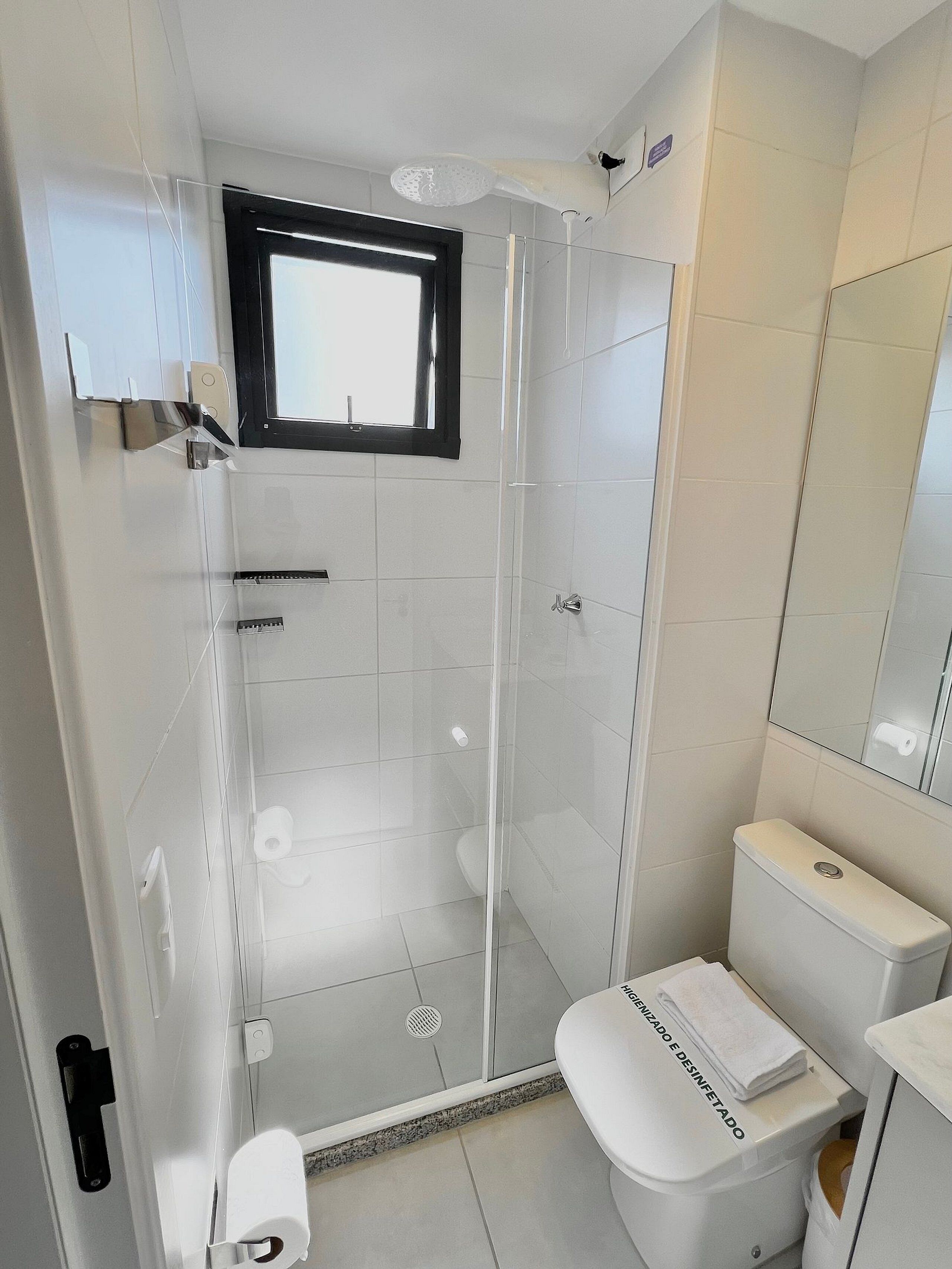 Une salle de bain moderne dotée d’une douche à parois de verre, de toilettes et d’un lavabo.