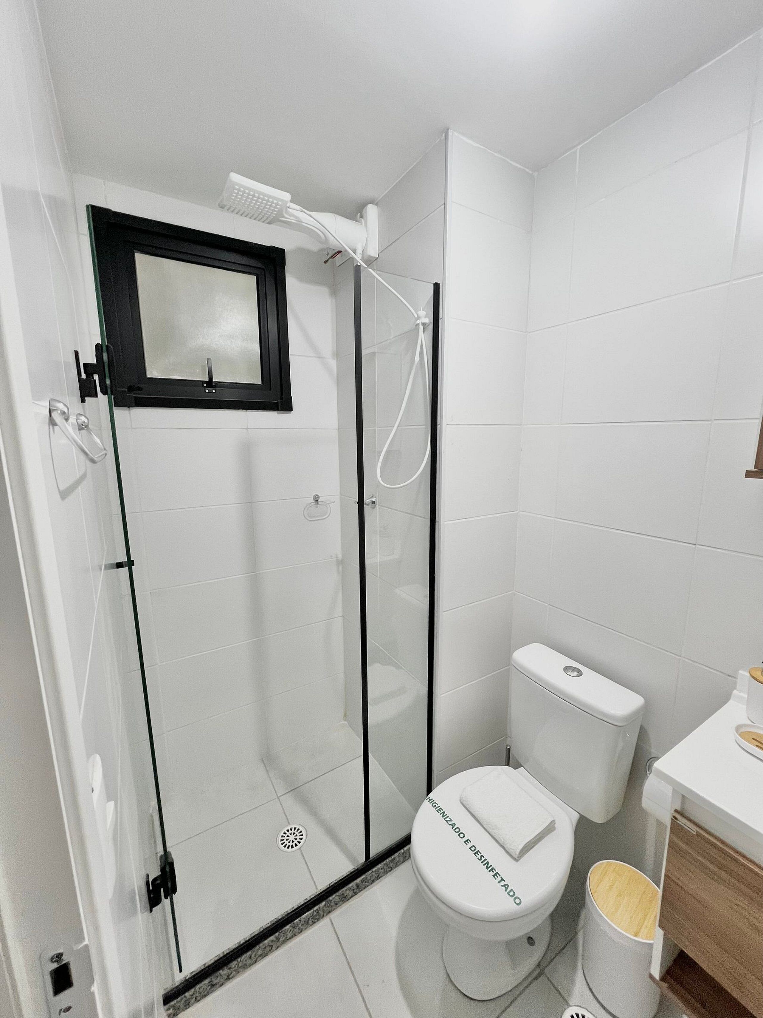 Uma casa de banho moderna com cabine de duche em vidro, sanita e lavatório.