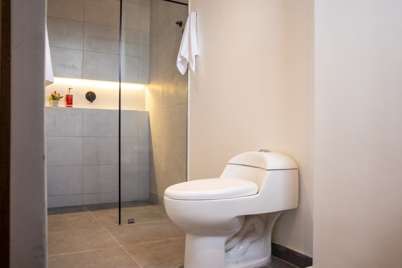 A modern bathroom with a toilet, a glass shower enclosure, and a towel hanging on the wall.