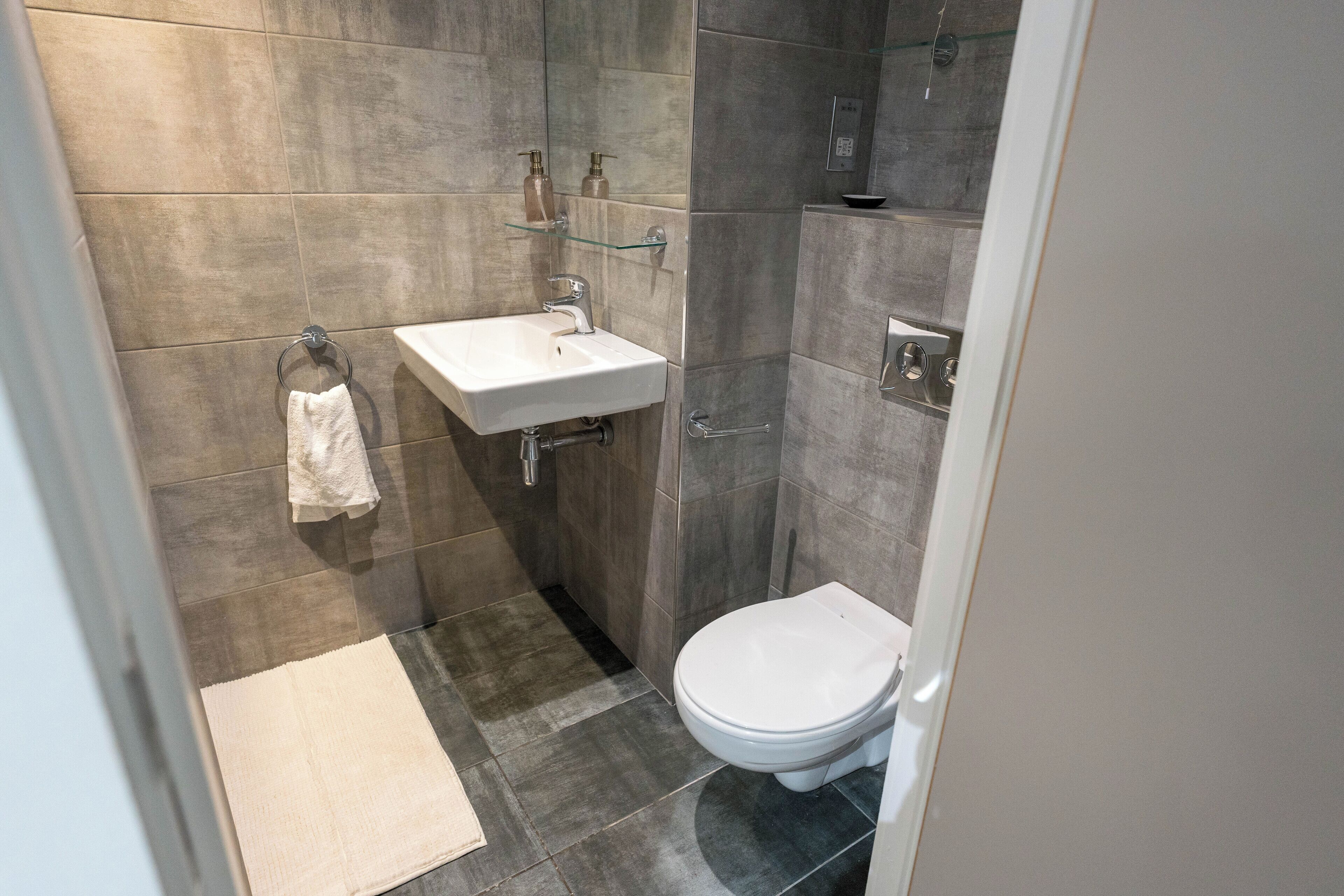 A modern bathroom with a white sink, toilet, and glass shower enclosure.