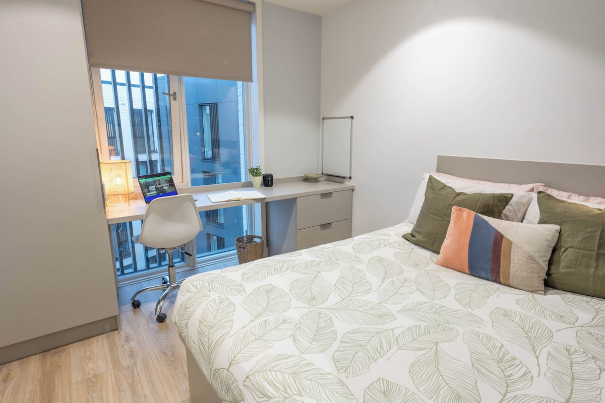 Un dormitorio con cama, escritorio y silla.