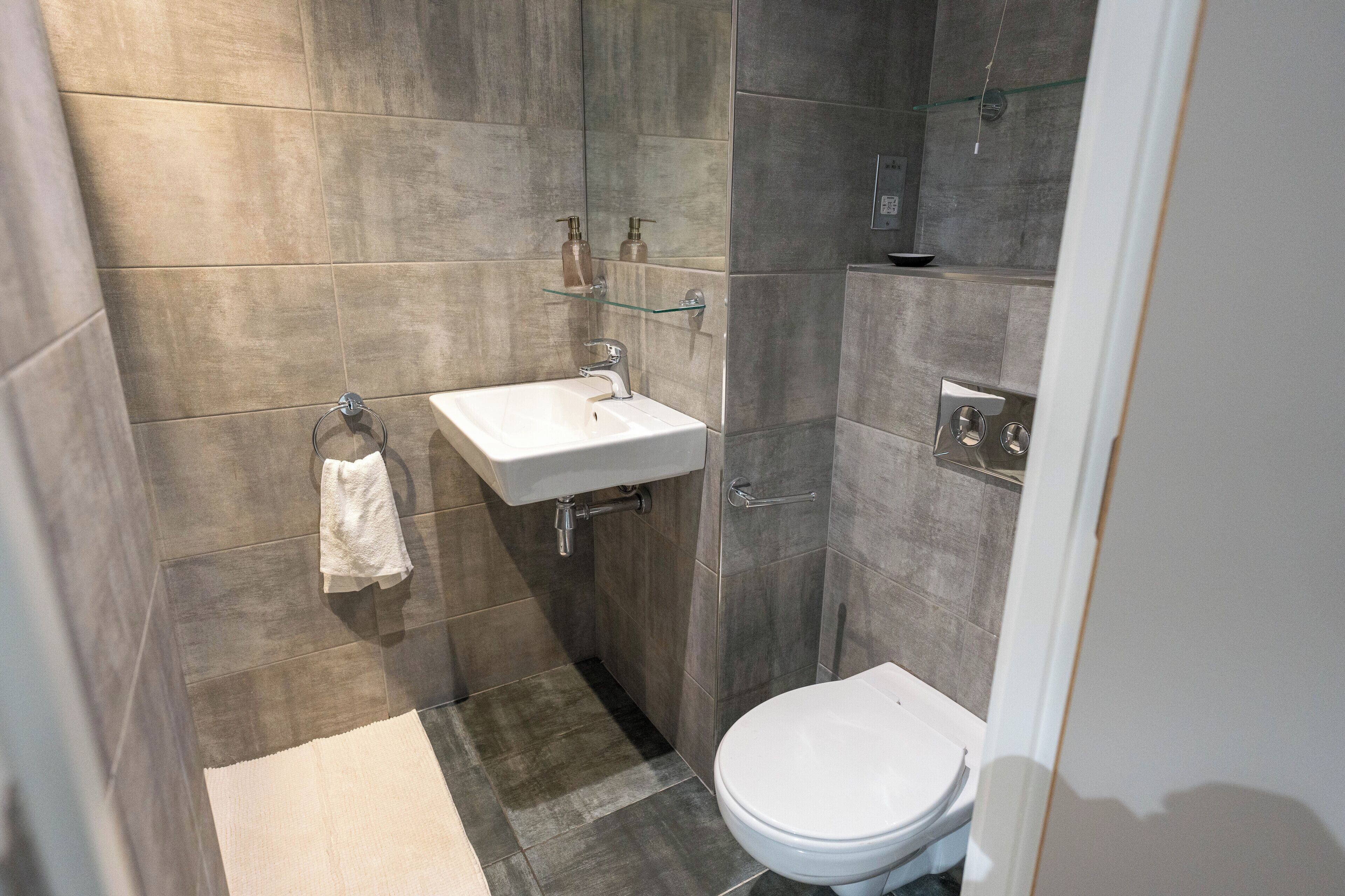 A modern bathroom with a white sink, toilet, and glass shower enclosure.