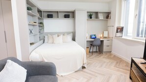 A modern bedroom with a bed, a desk, and shelving. - City HideAway (Galway)