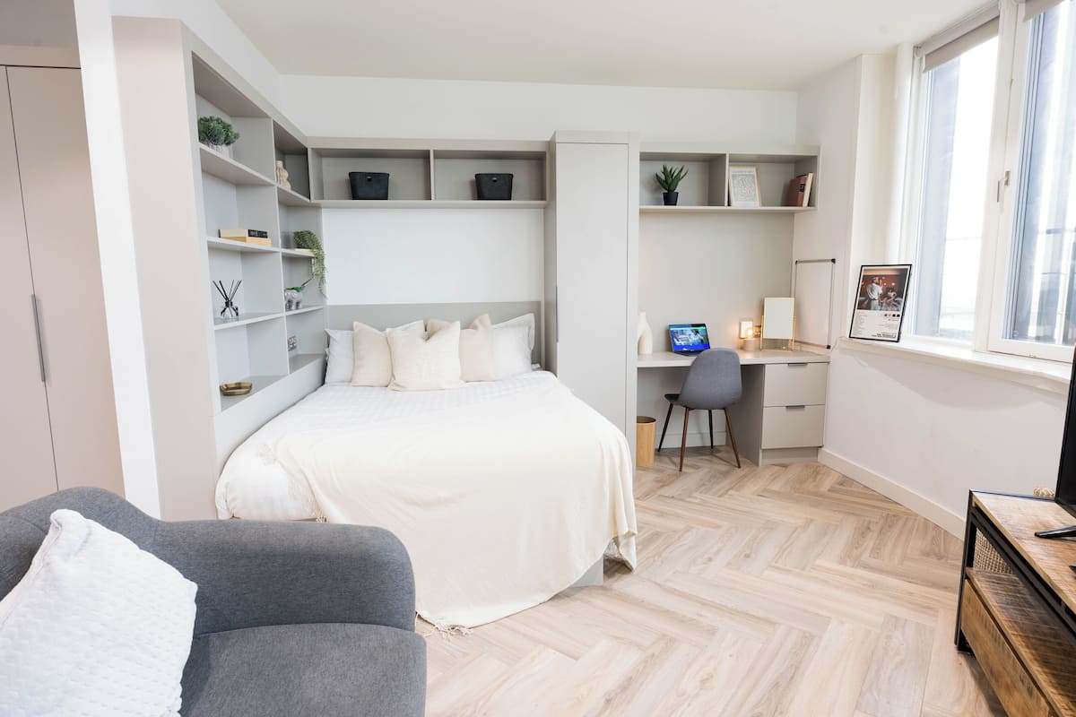 Un dormitorio moderno con cama, escritorio y estanterías.