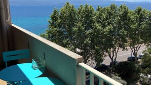 A balcony with turquoise furniture, overlooking a coastal view with trees and a distant shoreline. - Ajaccio center ville magnifique appartement neuf vue mer 5p plage wifi parking (Ajaccio)