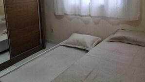 A bedroom with two beds, a wooden wardrobe, and a window with curtains. - Apartment in Belém cop30/2025 (Coqueiro Ananindeua)