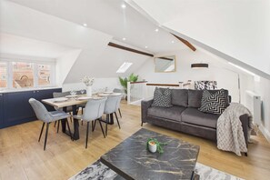 Un loft moderno con comedor, sofá con cojines estampados y una mesa de centro de mármol.