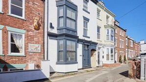 A row of terraced houses with distinct architectural styles, including bay windows and a mix of brick and white facades. - Host Stay Admiral s View (Whitby)