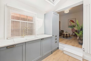Kitchen with sink, gold faucet, and dining area with small table and chairs.