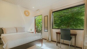 Une chambre à coucher avec un lit, un bureau et une fenêtre donnant sur un paysage verdoyant.