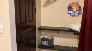 Une chambre d’hôtel avec un panneau indiquant « Mountain Top Park », un coffre-fort et une serviette posée sur une étagère.