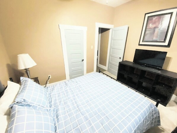 A bedroom with a bed, a TV, a dresser, and two doors.