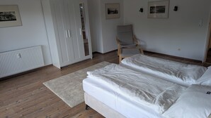 A bedroom with a bed, a wardrobe, a chair, and a radiator. - Neckar View Apartment near Heidelberg | Balcony & Parking (Neckarsteinach)
