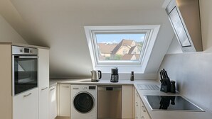 A compact kitchen with a skylight, a washing machine, a coffee maker, and a sink. - Neckar View Apartment near Heidelberg | Balcony & Parking (Neckarsteinach)