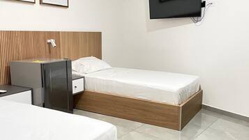 A hotel room with two beds, a TV mounted on the wall, and a wooden headboard.
