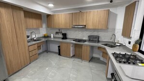 Une cuisine moderne avec des meubles en bois, un évier en acier inoxydable et une cuisinière à gaz.